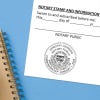 Arizona notary stamp impression on jurat form next to spiral notebook on blue background.