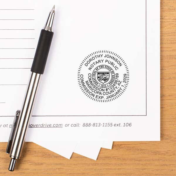 Arizona notary stamp impression on document with striped pen on wooden desk.