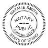 Round Idaho notary public stamp next to black and white self-inking stamp.