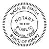 Round Idaho notary public stamp next to black and white self-inking stamp.