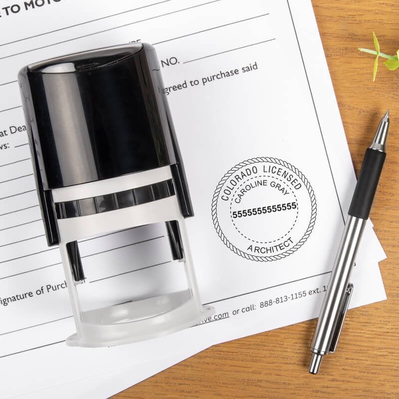 The State of Colorado Architect Seal impression on a document next to the stamp body and a pen