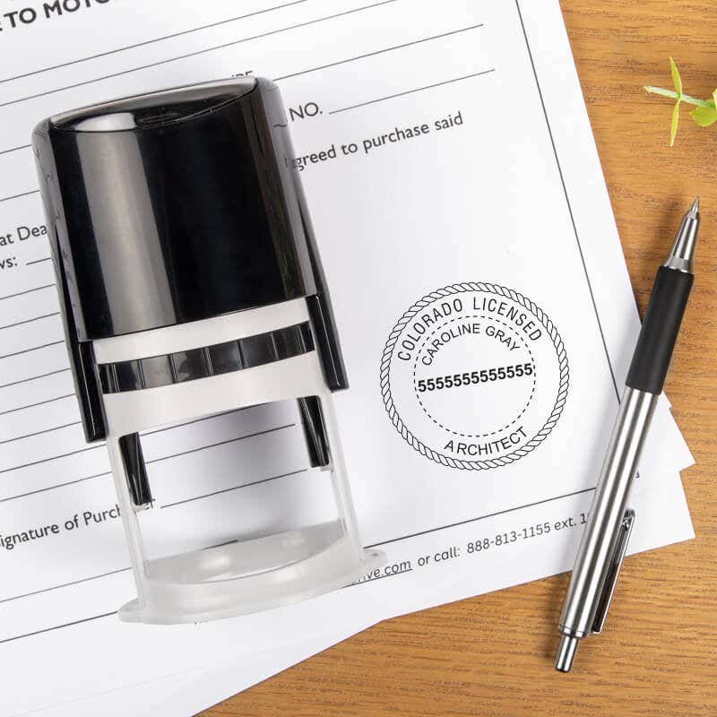 The State of Colorado Architect Seal impression on a document next to the stamp body and a pen