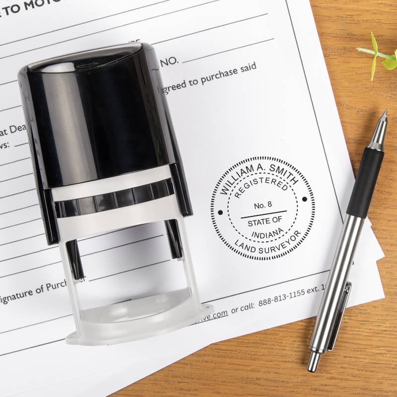 A self-inking stamp and a pen placed next to the State of Indiana Land Surveyor Seal