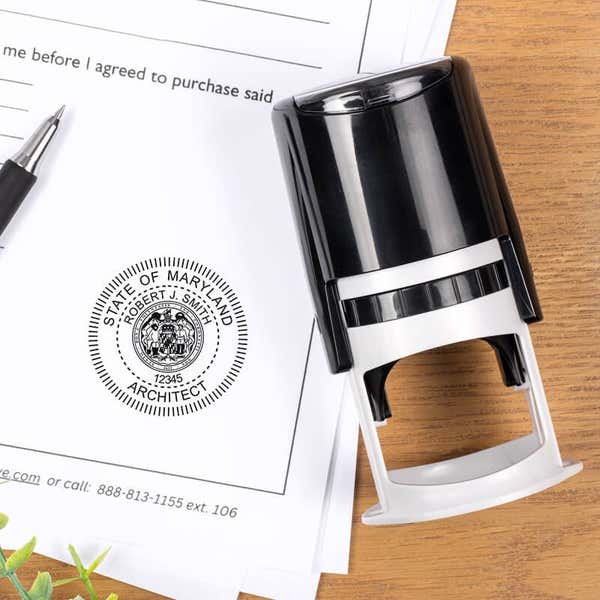 Maryland architect stamp impression on document beside self-inking stamp and pen.