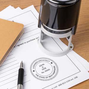 The State of New Hampshire Architect Seal at the bottom of a document with the self-inking stamp and a pen