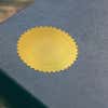 Example of Custom Initial Embosser Impression on Gold seal sticker on blue book