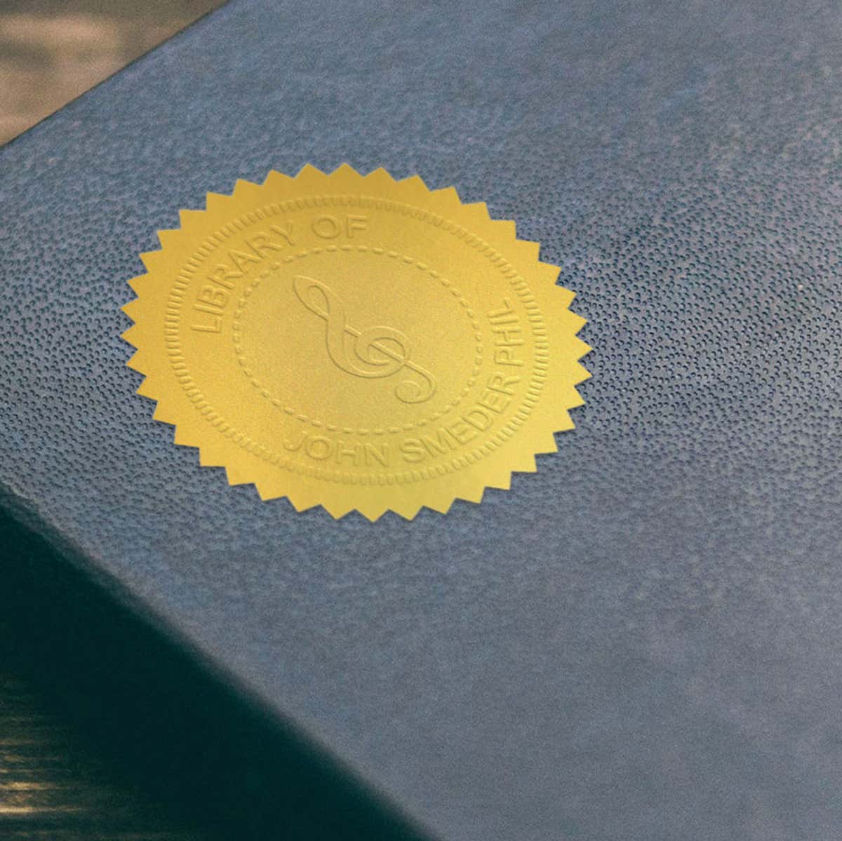 Example of Treble Clef Music Symbol Embosser impression on gold seal on blue book