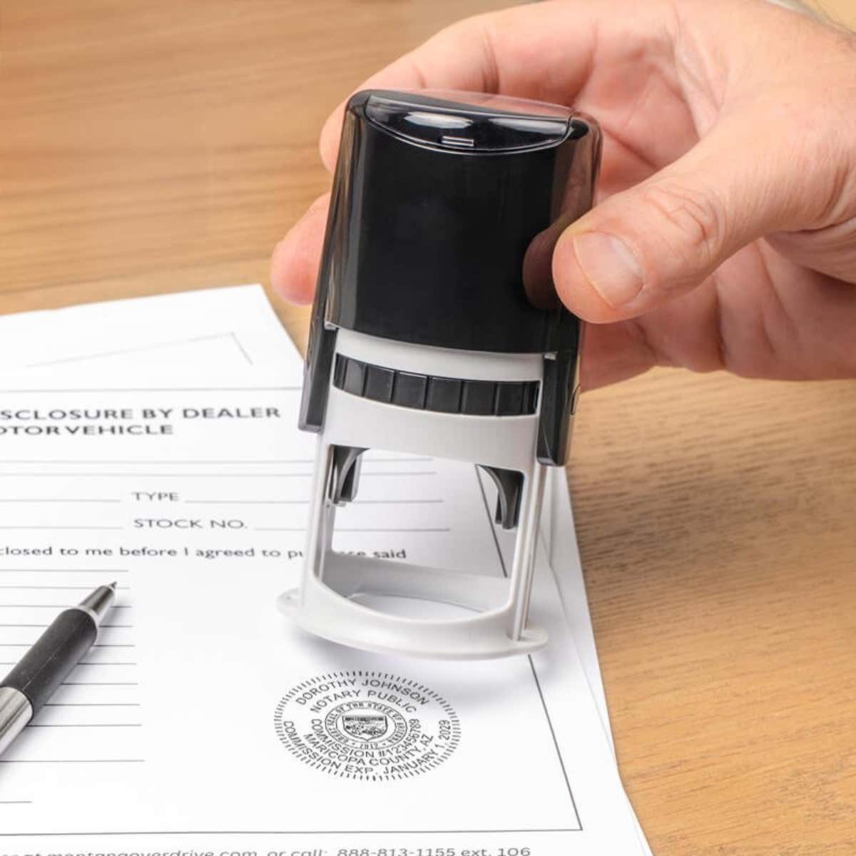 Hand pressing down with an Arizona notary stamp, showing a labeled stamp impression. 
