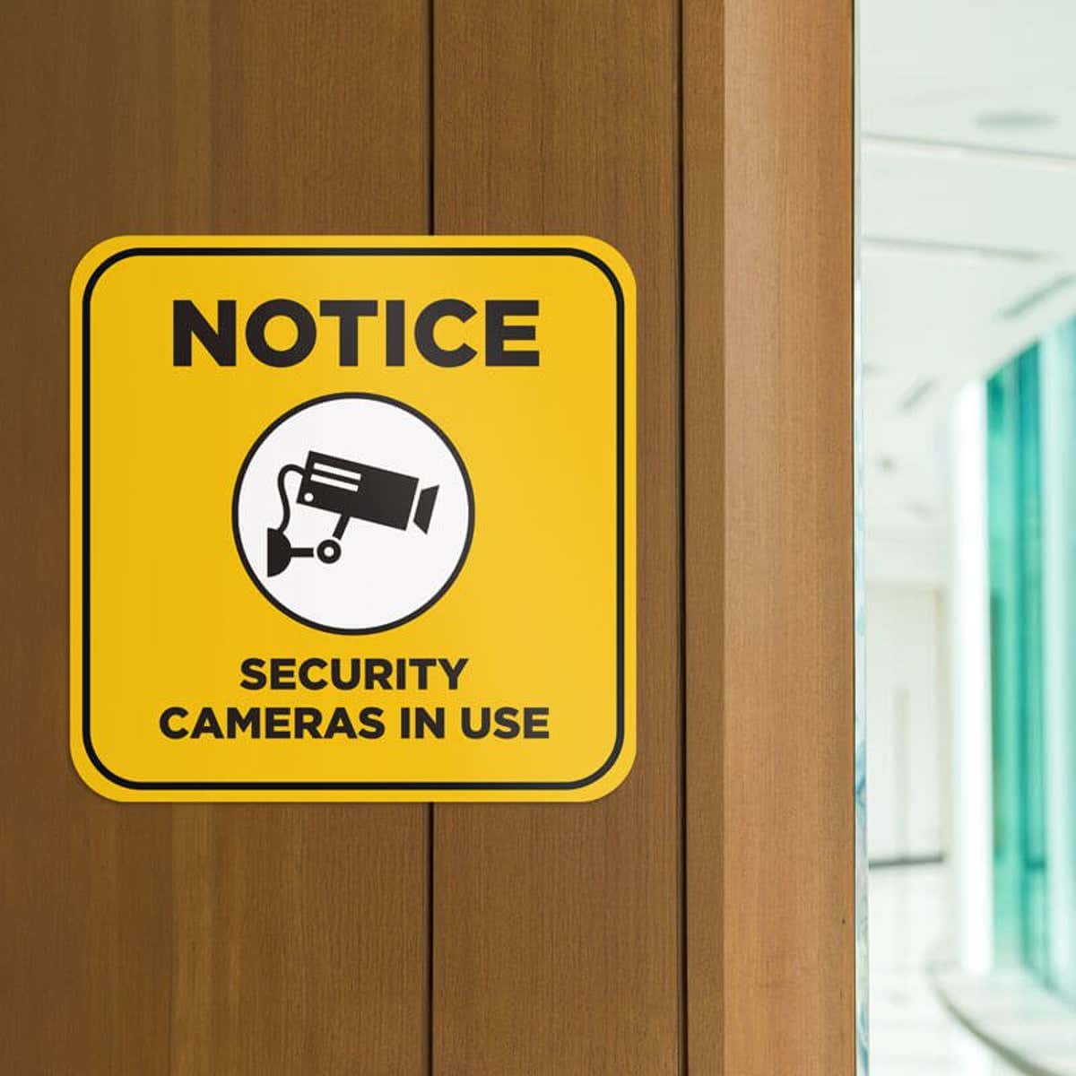 Yellow background custom sign with bold black text reads Notice security cameras in use and has surveillance camera icon