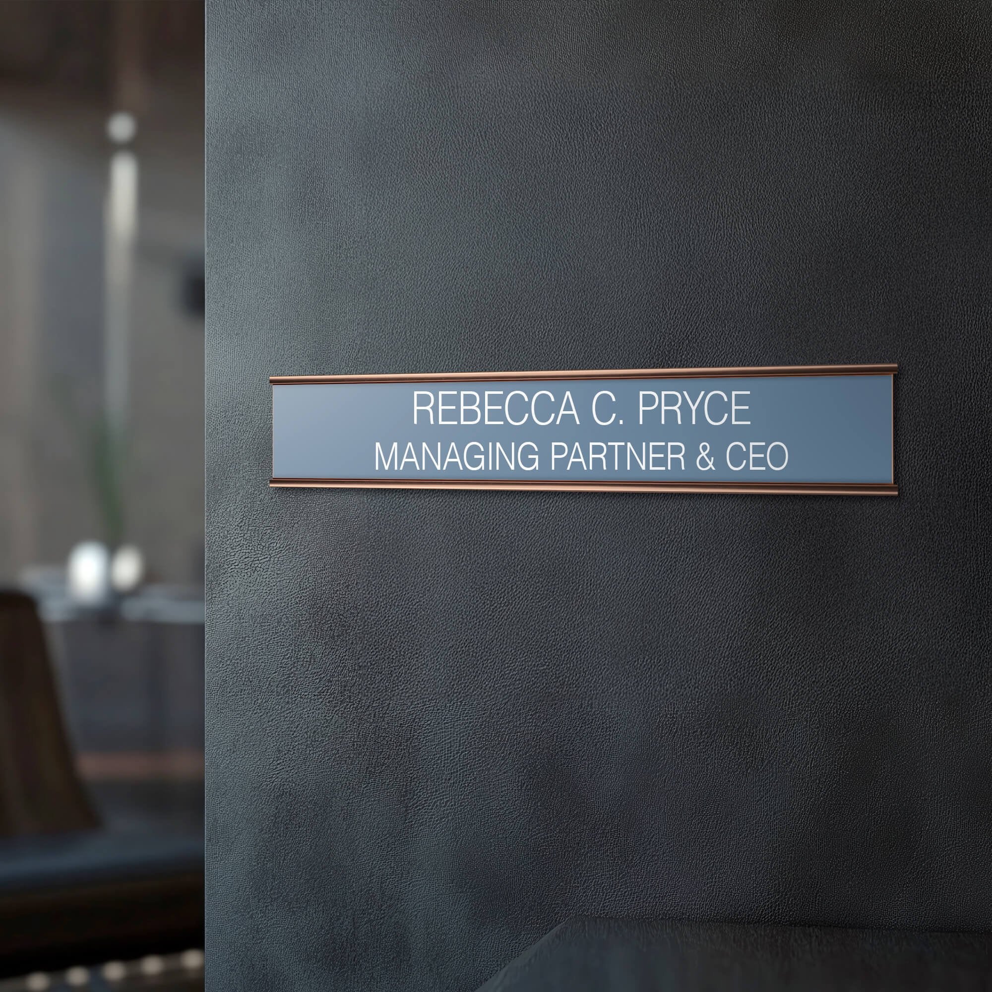 A gray name plate with a rose gold aluminum holder by an office