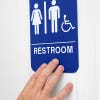 A person's hand feeling the Braille on the sign