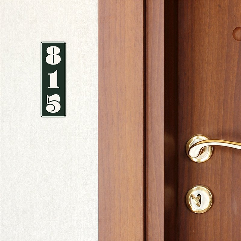 A green engraved plastic sign with a room number