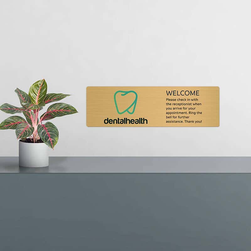 6x20 printed brass sign displayed by a front desk