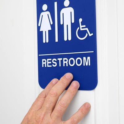 A person's hand feeling the Braille on the sign