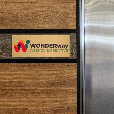 6x16 printed brass sign displayed on a wooden wall