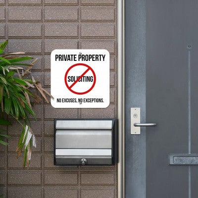 Private property no soliciting sign hung outside on the wall next to the front door reading "No excuses, no exceptions"