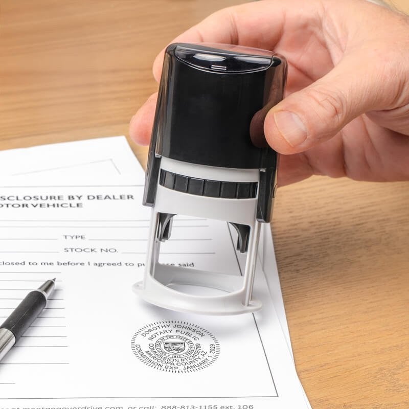 Hand pressing down with an Arizona notary stamp, showing a labeled stamp impression. 