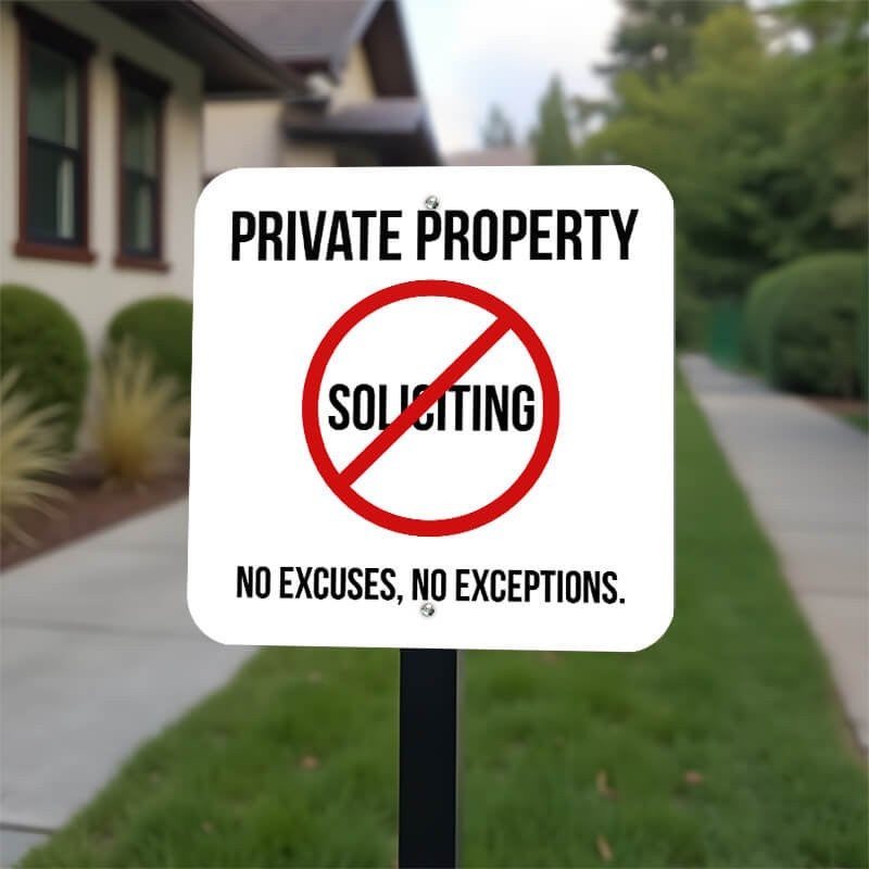 Bold private property sign with a no soliciting symbol on a white background on a yard stake outside in the front yard