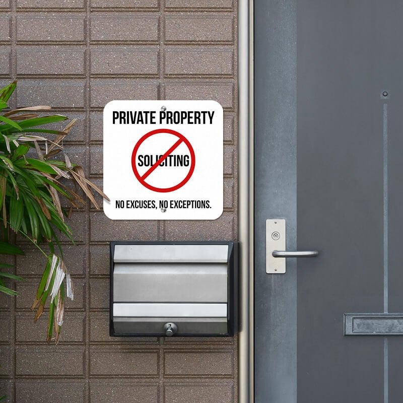Private property no soliciting sign hung outside on the wall next to the front door reading "No excuses, no exceptions"