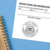 Arizona notary stamp impression on jurat form next to spiral notebook on blue background.