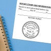 Notary public stamp impression on signed document above notebook