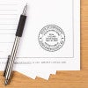 Florida notary stamp impression on document with striped pen on wood desk surface.