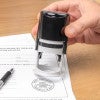 Close view of a notary applying a round seal to official paperwork.