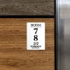 An engraved plastic sign with a room number and hotel logo