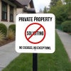 Bold private property sign with a no soliciting symbol on a white background on a yard stake outside in the front yard
