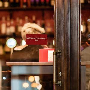 Red Plastic Sign With White Text Saying Maximum Occupancy 268